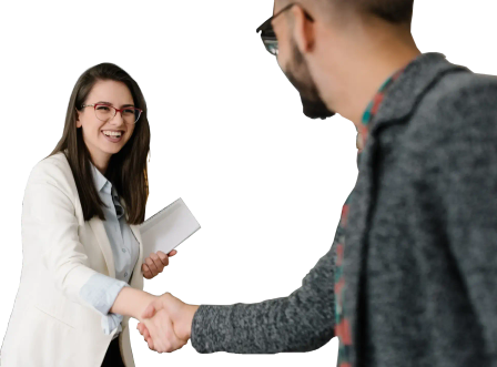 Two smiling people holding documents and shaking hands
