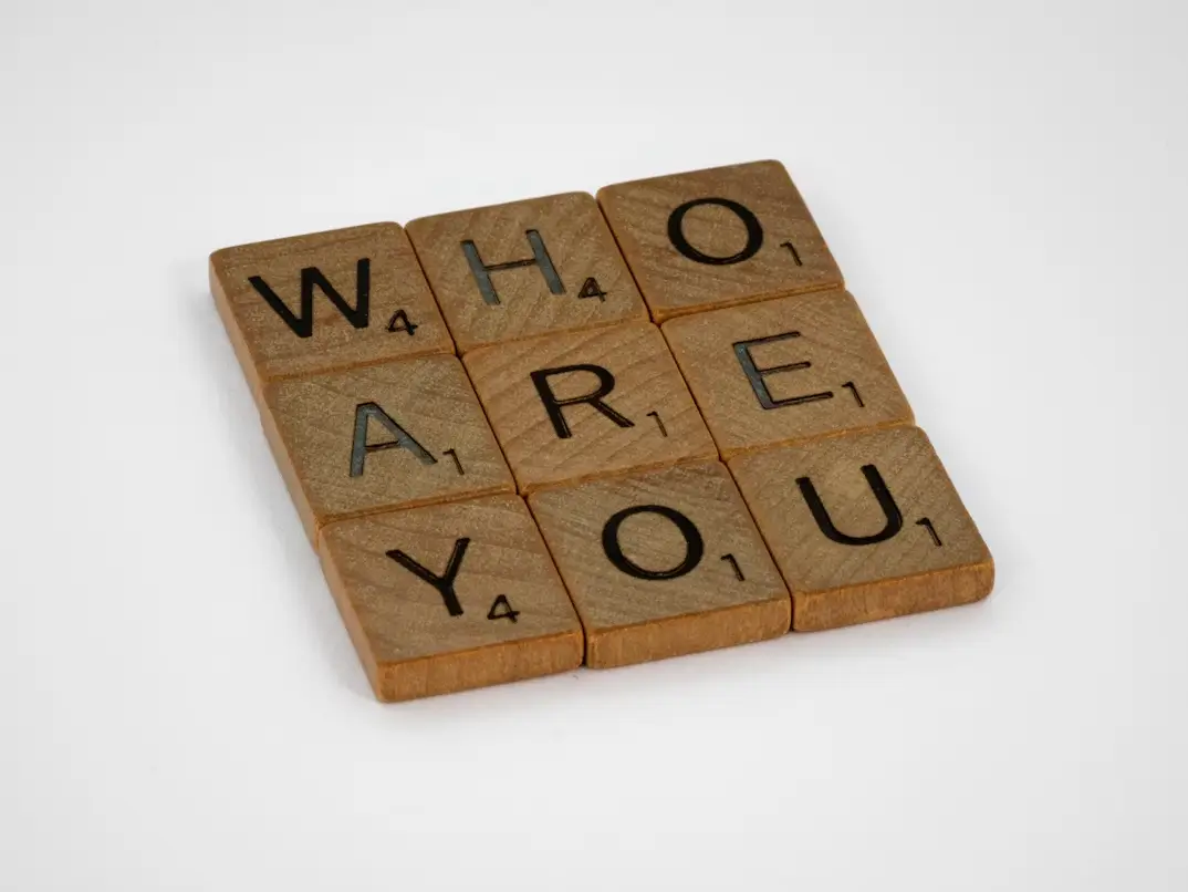 Scrabble wooden tiles spelling out “Who are you”.